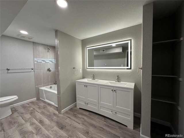 bathroom featuring toilet, visible vents, a sink, and wood finished floors