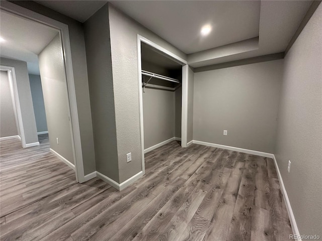 unfurnished bedroom featuring a closet, wood finished floors, and baseboards