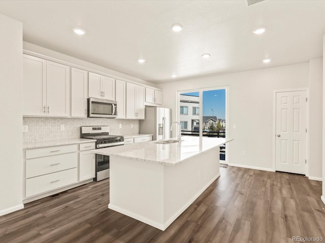 kitchen featuring dark wood-type flooring, white cabinetry, tasteful backsplash, a center island with sink, and appliances with stainless steel finishes