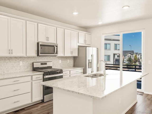 kitchen featuring sink, appliances with stainless steel finishes, a kitchen island with sink, light stone countertops, and white cabinets