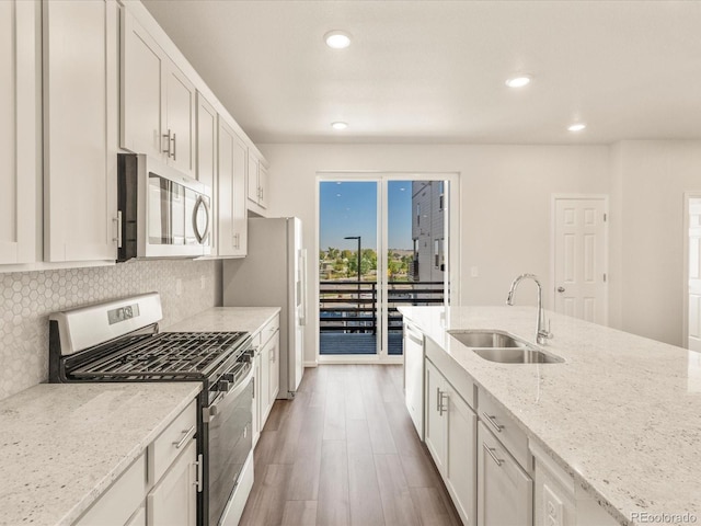 kitchen with sink, stainless steel appliances, light stone countertops, decorative backsplash, and white cabinets