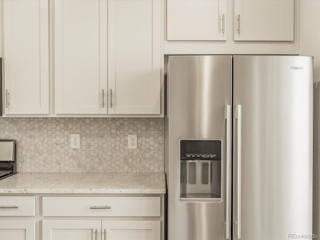 kitchen featuring stainless steel fridge, light stone countertops, decorative backsplash, and white cabinets