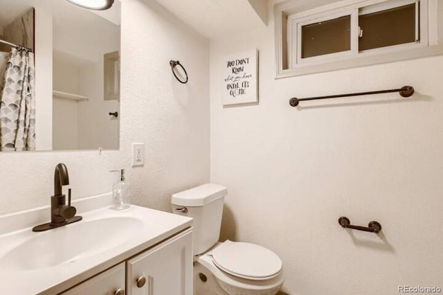 bathroom featuring vanity, toilet, and walk in shower