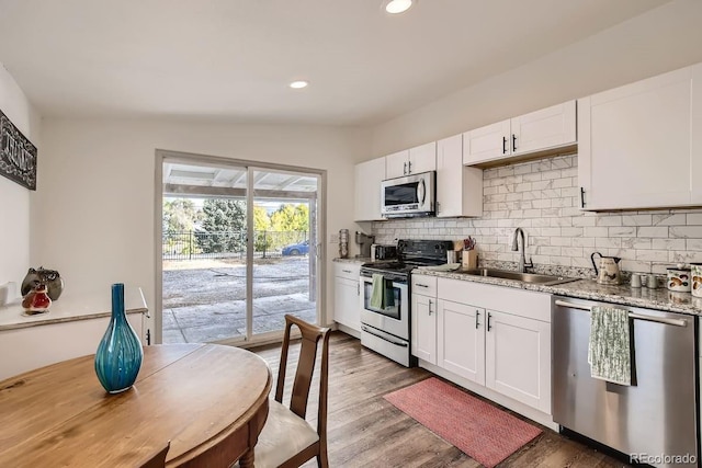 kitchen featuring appliances with stainless steel finishes, white cabinetry, lofted ceiling, and sink