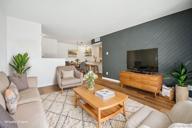 living room featuring light hardwood / wood-style flooring and wood walls