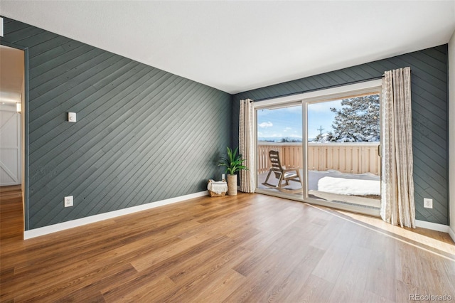 spare room featuring hardwood / wood-style floors and wooden walls