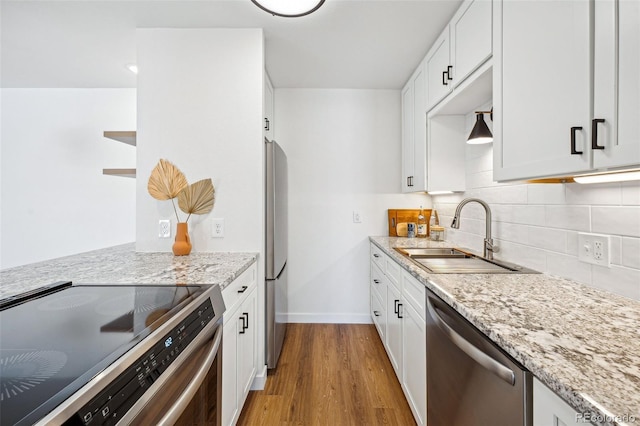 kitchen with light wood-type flooring, stainless steel appliances, sink, and white cabinets