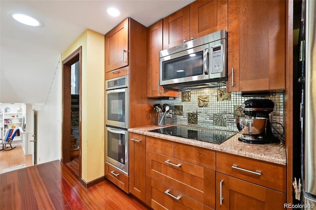 8664 E Monmouth Pl, Denver, CO 80237 - kitchen with appliances with stainless steel finishes, dark wood-style floors, brown cabinetry, and recessed lighting