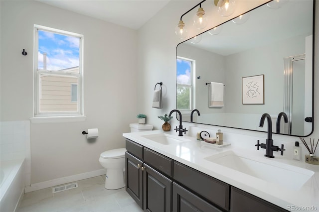 bathroom with tile patterned floors, a washtub, vanity, and toilet