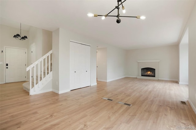 unfurnished living room with light hardwood / wood-style floors and an inviting chandelier