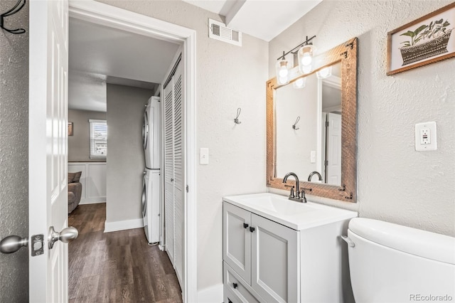 4512 S Yank St, Morrison, CO 80465 - bathroom with stacked washer and clothes dryer, vanity, wood finished floors, and a textured wall