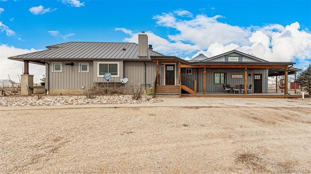 rear view of house with metal roof, a standing seam roof, and board and batten siding