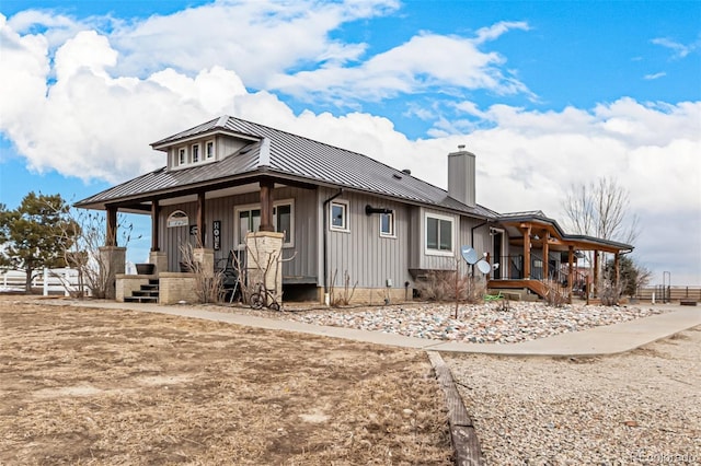 view of front of home with a chimney, metal roof, covered porch, a standing seam roof, and board and batten siding