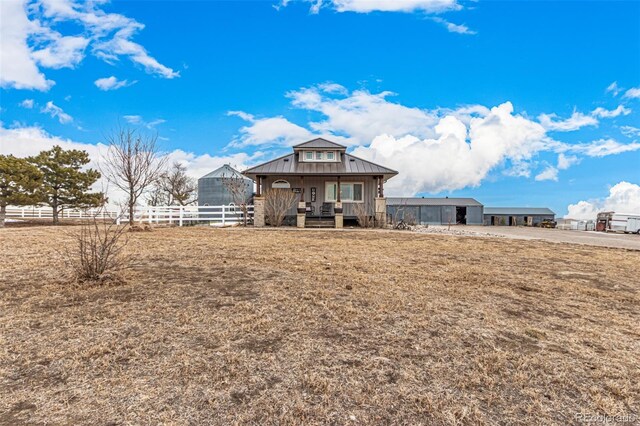 back of property with metal roof, a standing seam roof, and fence