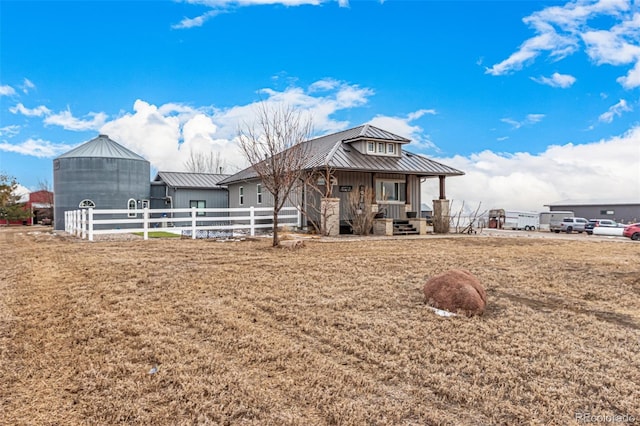 view of front of property featuring a porch, a standing seam roof, metal roof, fence, and a front lawn