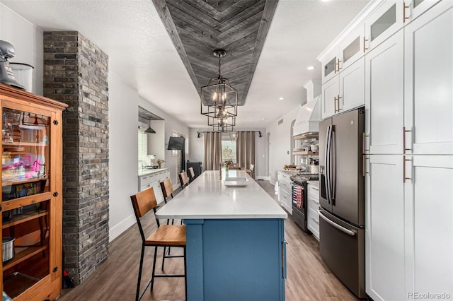 kitchen featuring stainless steel fridge, gas range, a center island, premium range hood, and a sink