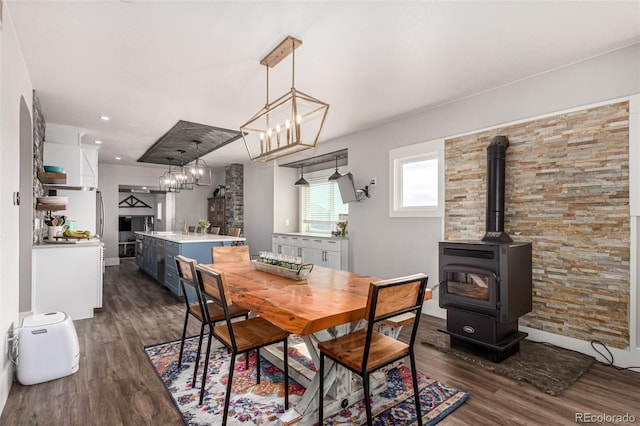 dining area with a wood stove, dark wood-style flooring, and recessed lighting