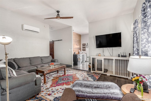 living area featuring a barn door, a wall unit AC, wood finished floors, and a ceiling fan