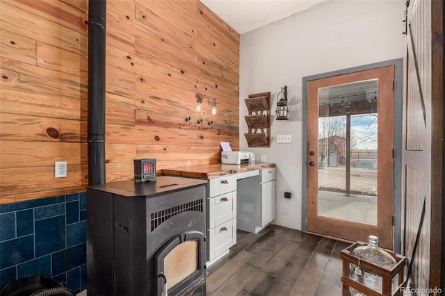 bar featuring dark wood-style floors, wood walls, and a wood stove