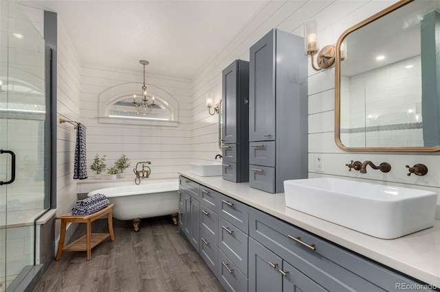 bathroom with double vanity, a soaking tub, a sink, a shower stall, and wood finished floors