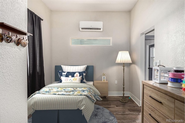 bedroom with baseboards, an AC wall unit, and wood finished floors