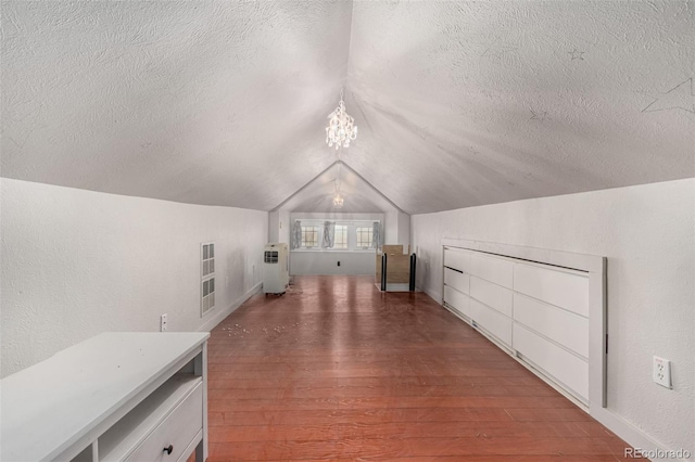 additional living space featuring lofted ceiling, a textured wall, a textured ceiling, a notable chandelier, and wood finished floors