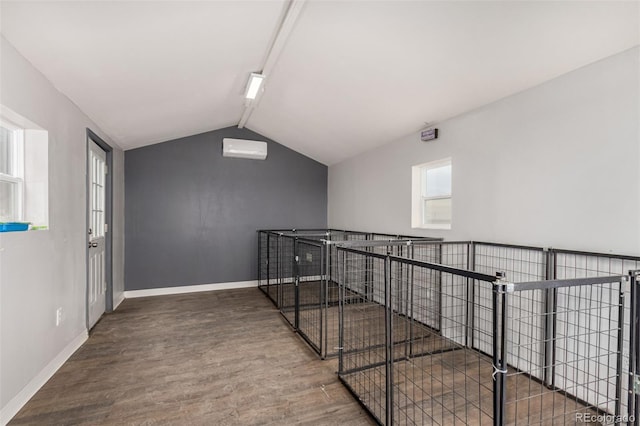 corridor featuring lofted ceiling, a wall unit AC, baseboards, and wood finished floors