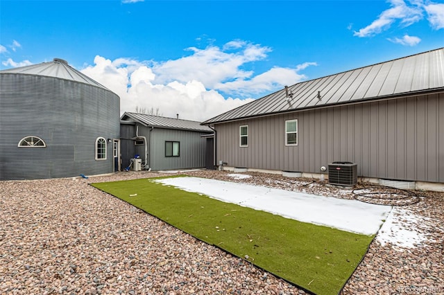 rear view of property featuring central air condition unit, a standing seam roof, and metal roof