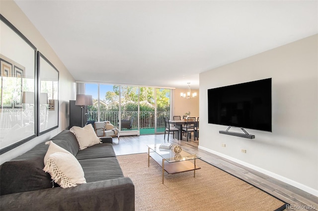 living area with a chandelier, plenty of natural light, baseboards, and wood finished floors