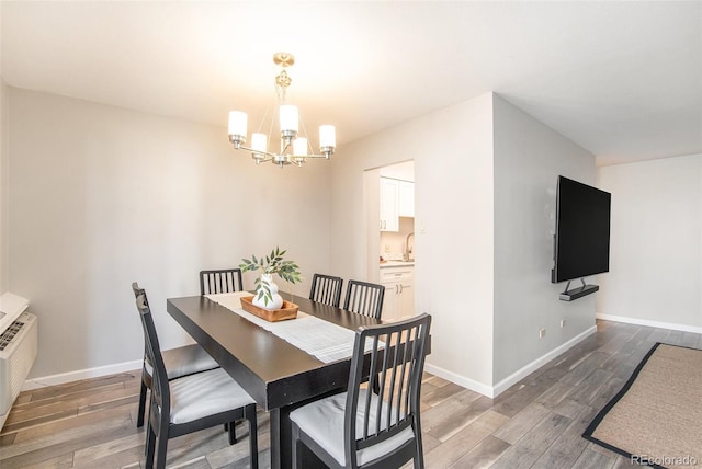 dining area with a notable chandelier, baseboards, and light wood-style floors