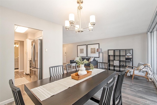 dining area featuring a chandelier, baseboards, and wood finished floors