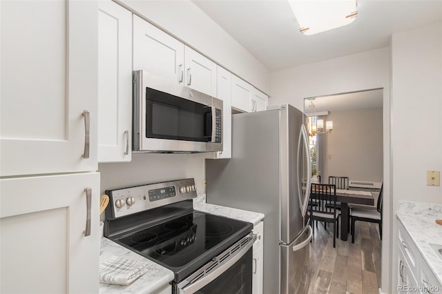 kitchen with an inviting chandelier, white cabinets, light wood finished floors, and appliances with stainless steel finishes