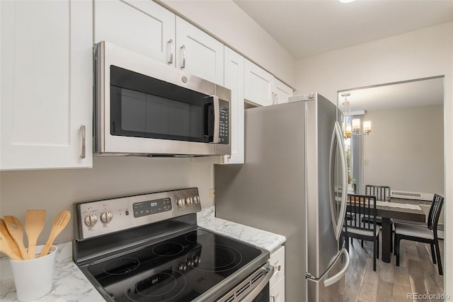 kitchen featuring stainless steel appliances, light stone countertops, white cabinets, and light wood-style flooring