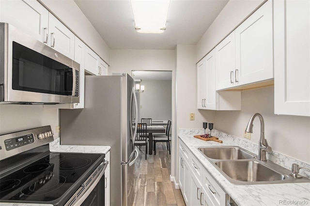 kitchen featuring light wood-style flooring, a sink, light countertops, white cabinets, and appliances with stainless steel finishes