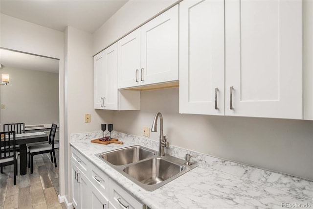 kitchen featuring a sink, light wood finished floors, light countertops, and white cabinetry