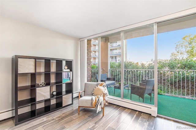 living area with baseboard heating, wood finished floors, and expansive windows