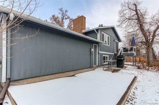 snow covered rear of property with a wooden deck