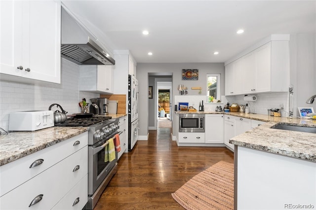 kitchen featuring white cabinetry, dark wood-type flooring, wall chimney exhaust hood, stainless steel appliances, and sink