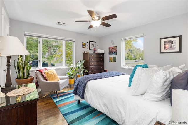 bedroom with multiple windows, ceiling fan, and dark hardwood / wood-style flooring