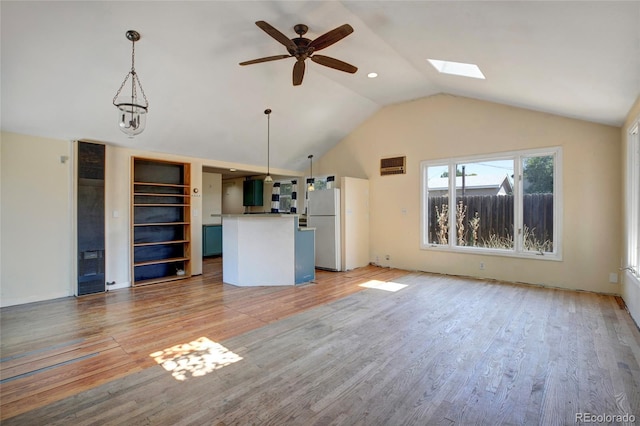 unfurnished living room featuring vaulted ceiling with skylight, hardwood / wood-style flooring, and ceiling fan