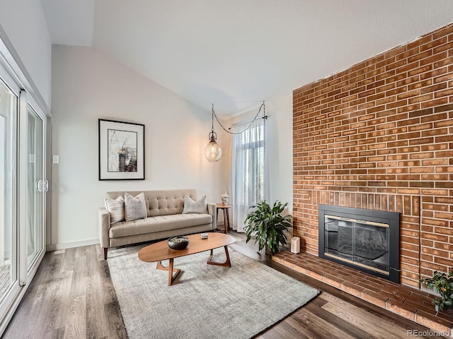 living room with hardwood / wood-style floors, lofted ceiling, and a fireplace