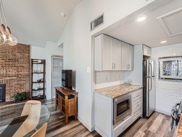 kitchen with white cabinets, appliances with stainless steel finishes, dark hardwood / wood-style floors, and light stone counters