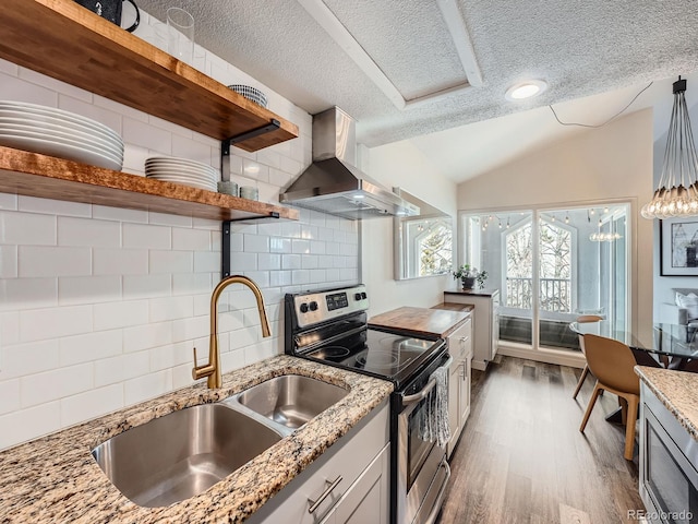 kitchen with backsplash, light stone counters, a textured ceiling, wall chimney range hood, and stainless steel electric range oven