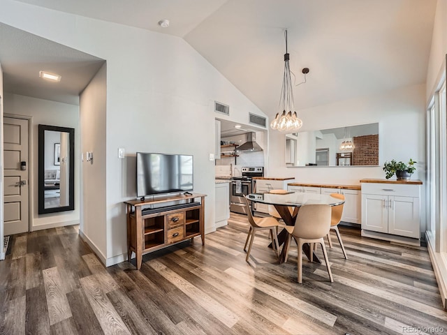 dining space with dark hardwood / wood-style flooring, lofted ceiling, and an inviting chandelier