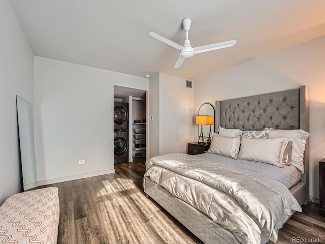 bedroom with ceiling fan, dark hardwood / wood-style flooring, and stacked washer / drying machine