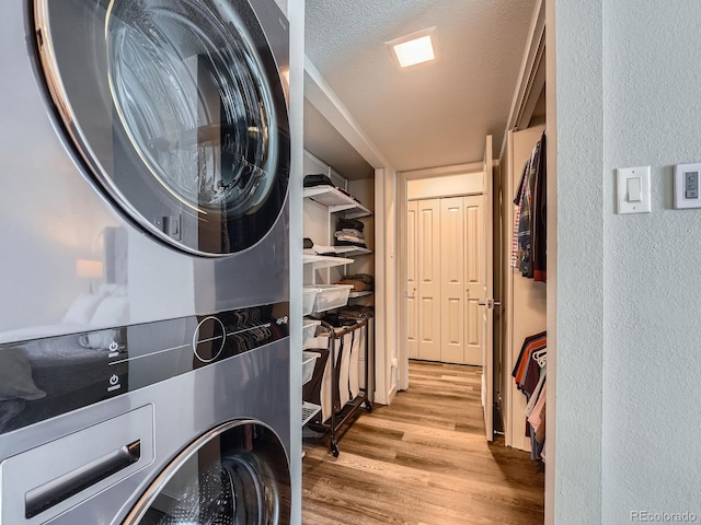 washroom featuring light wood-type flooring, a textured ceiling, and stacked washer / drying machine