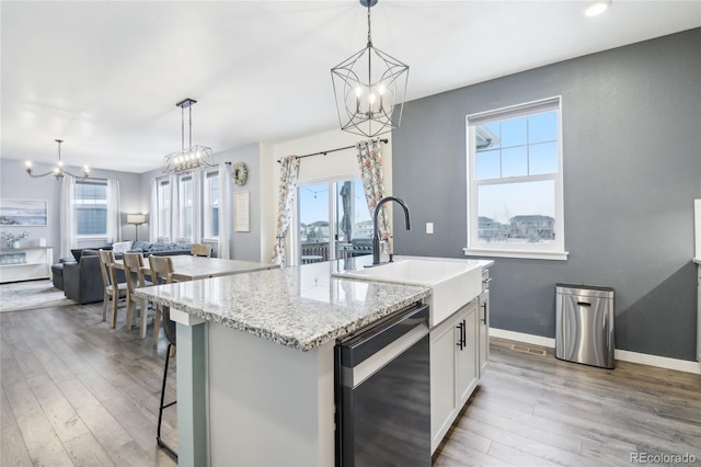 kitchen with black dishwasher, a healthy amount of sunlight, a sink, and wood finished floors