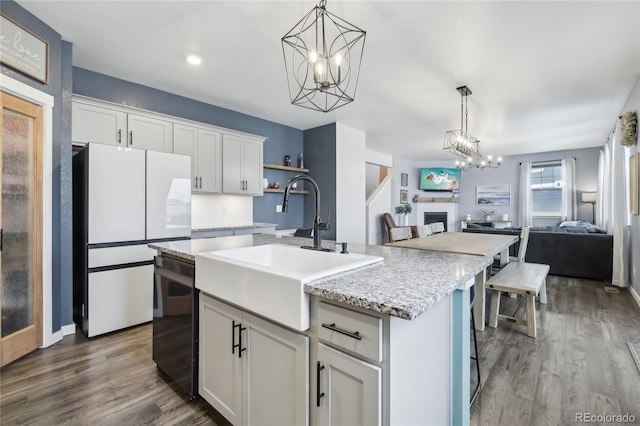 kitchen featuring a sink, open floor plan, freestanding refrigerator, dishwasher, and decorative light fixtures