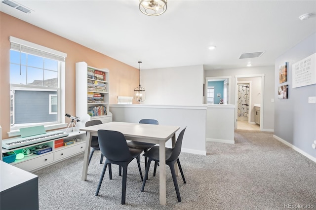 dining room featuring baseboards, visible vents, a chandelier, and light colored carpet