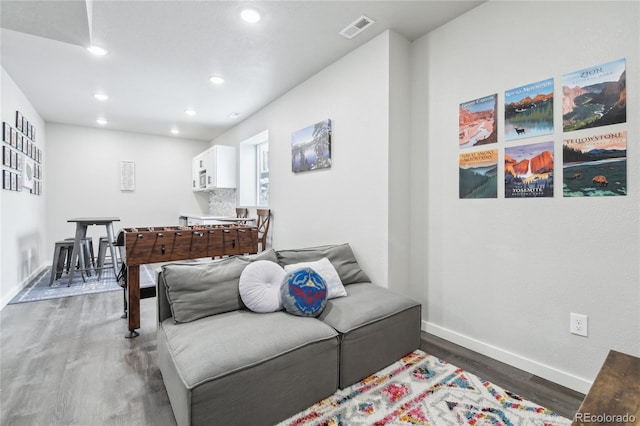 living area with dark wood-style flooring, recessed lighting, visible vents, and baseboards